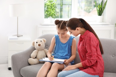 Young female psychologist working with little child in office