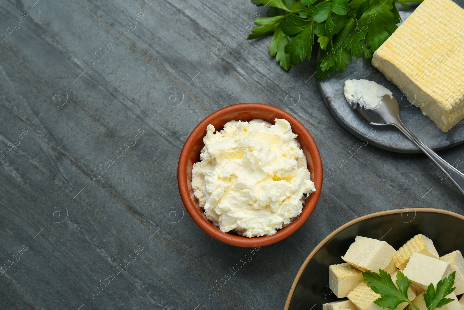 Photo of Delicious tofu cheese and parsley on black table, flat lay. Space for text