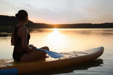 Photo of Woman paddle boarding on SUP board in river at sunset
