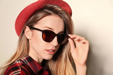 Photo of Young woman wearing stylish sunglasses on beige background