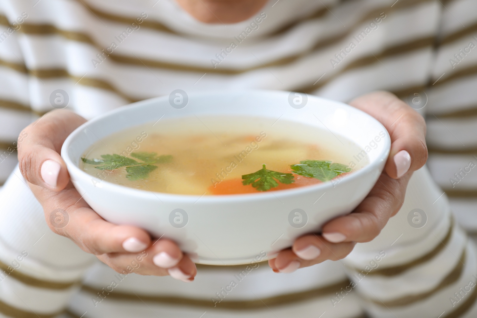 Photo of Young woman holding bowl of tasty soup, closeup