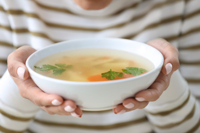 Photo of Young woman holding bowl of tasty soup, closeup