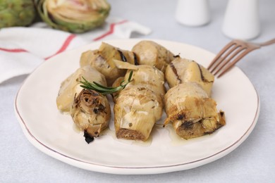 Delicious pickled artichokes with rosemary served on white table, closeup