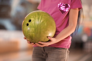 Photo of Little girl with ball in bowling club, closeup