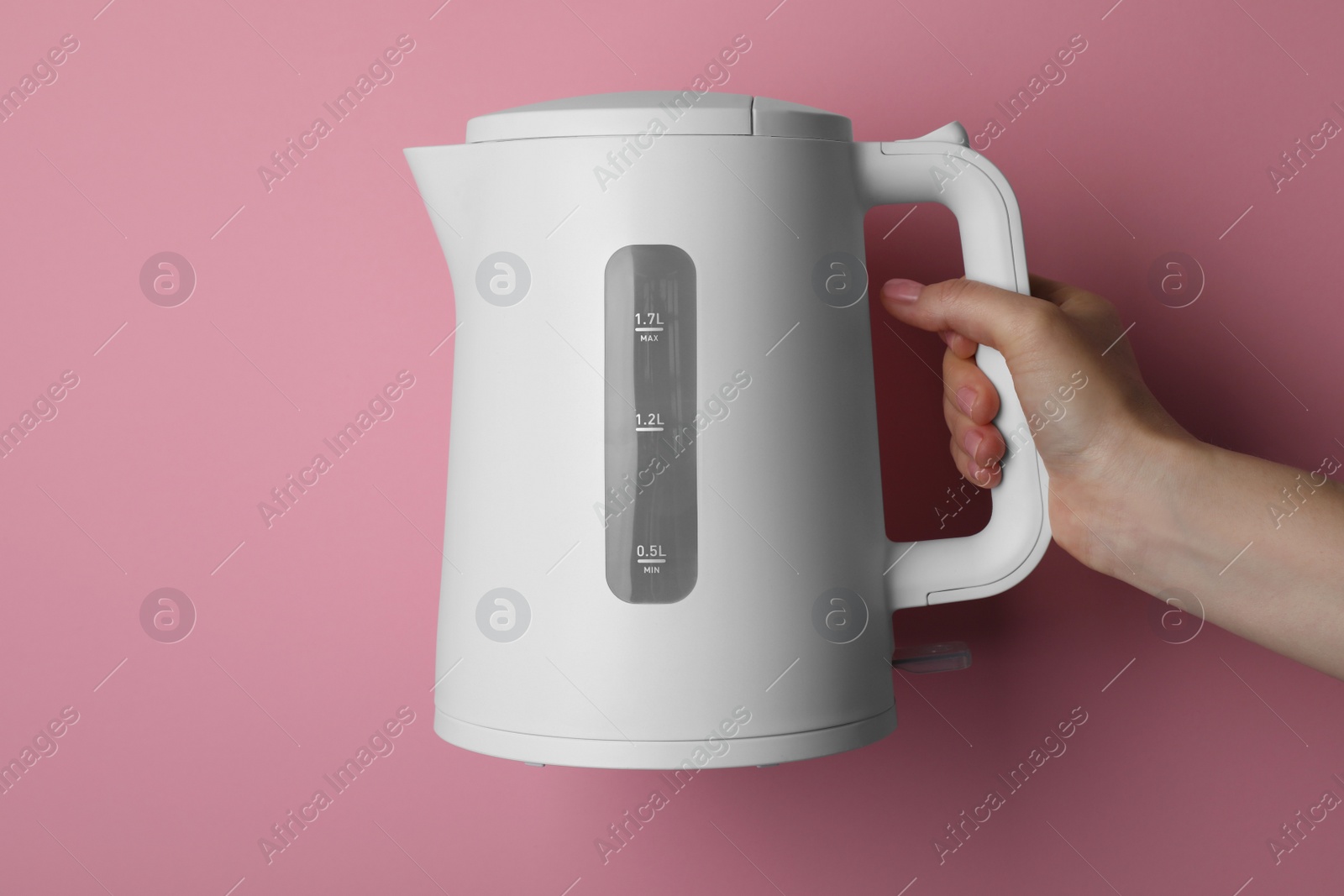 Photo of Woman holding modern electric kettle on pink background, closeup