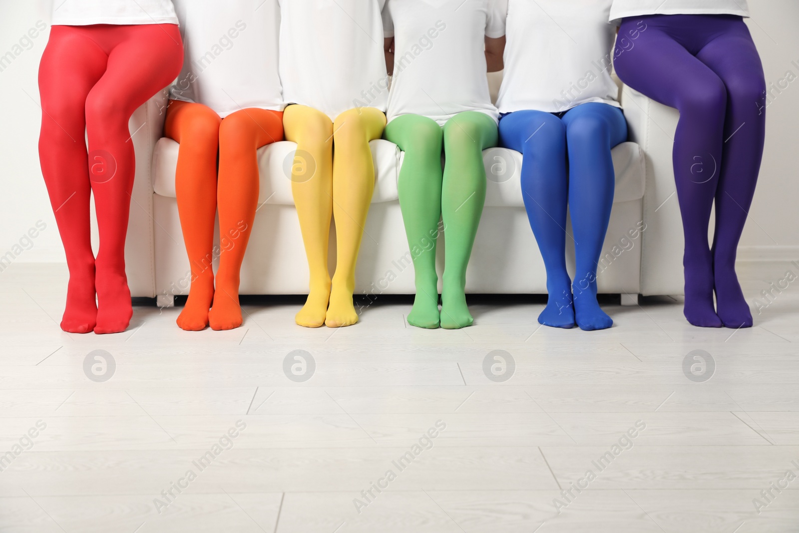 Photo of Women wearing colorful tights sitting on sofa indoors, closeup