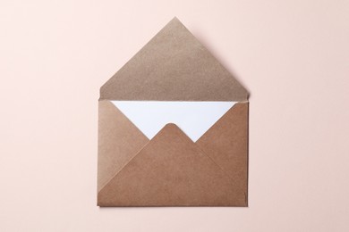 Photo of Letter envelope with card on beige background, top view