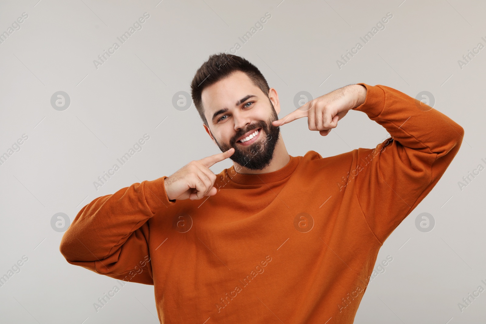 Photo of Man showing his clean teeth and smiling on gray background