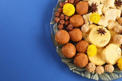 Photo of Diwali celebration. Tasty Indian sweets, spices and nuts on blue table, top view. Space for text