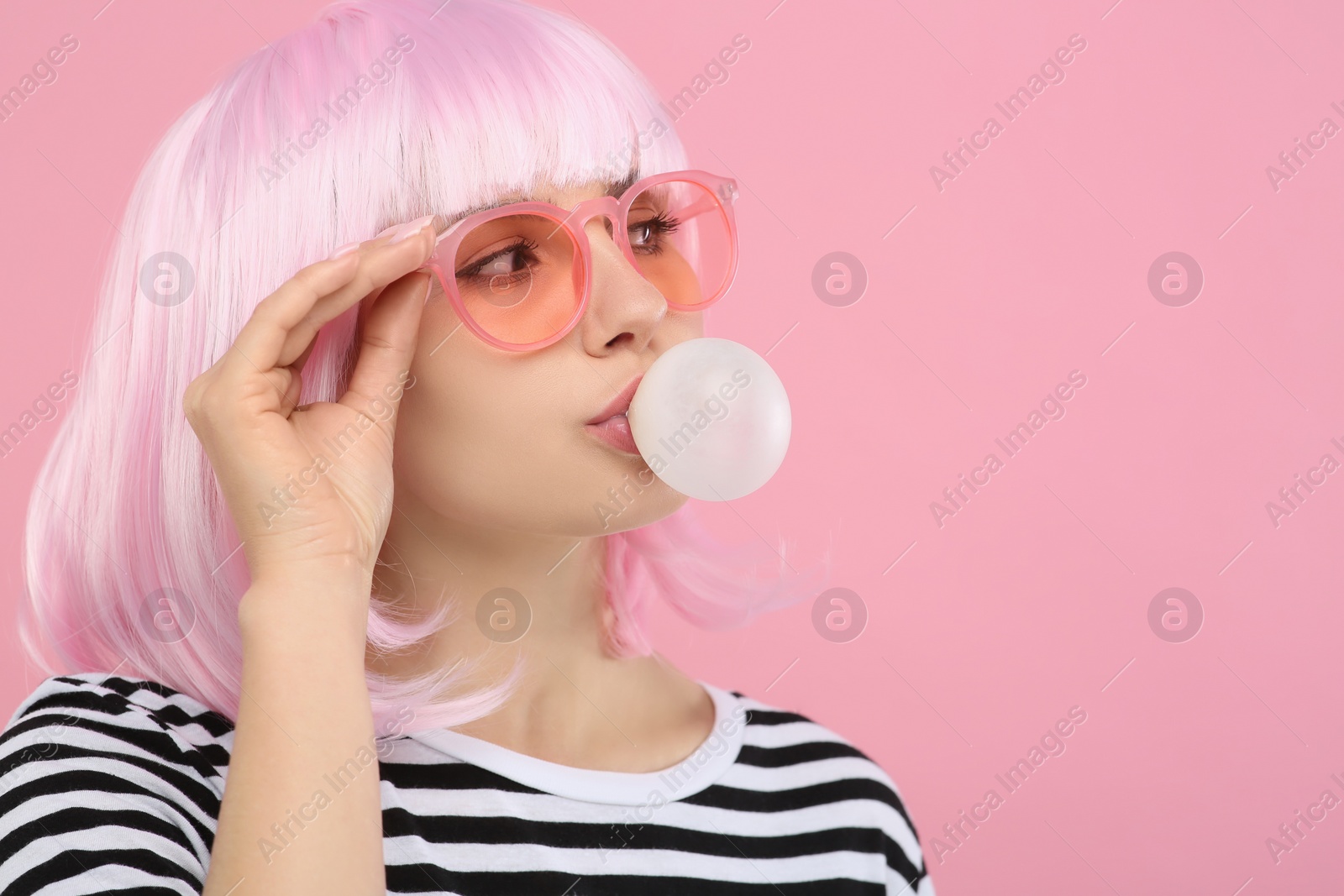 Photo of Beautiful woman in sunglasses blowing bubble gum on pink background, space for text