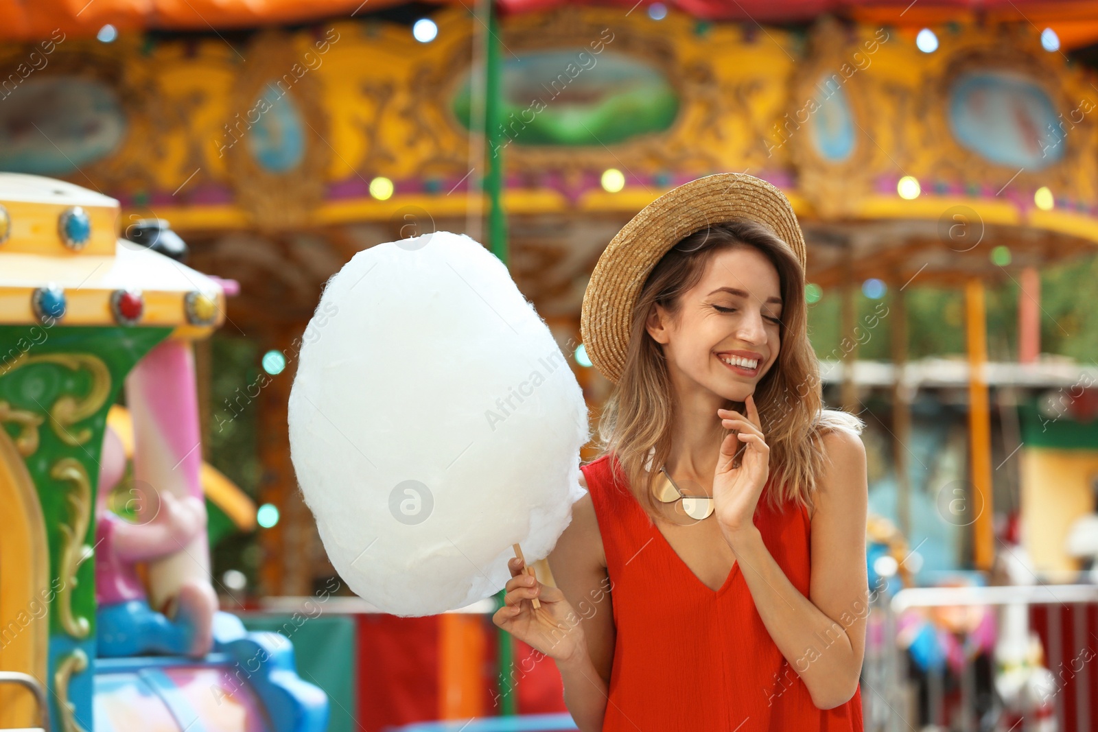 Photo of Happy young woman with cotton candy in amusement park
