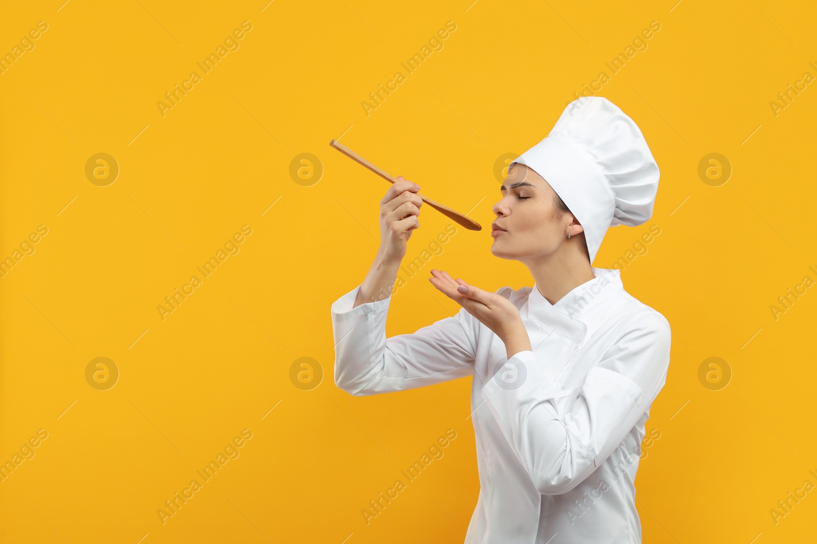 Photo of Female chef tasting something on orange background. Space for text