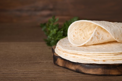 Photo of Wooden board with corn tortillas on table, space for text. Unleavened bread