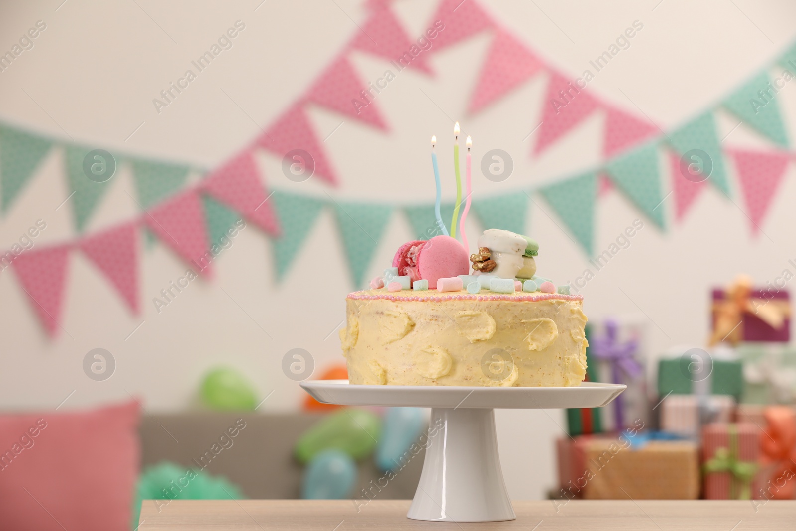 Photo of Delicious cake decorated with macarons and marshmallows on wooden table in festive room, space for text