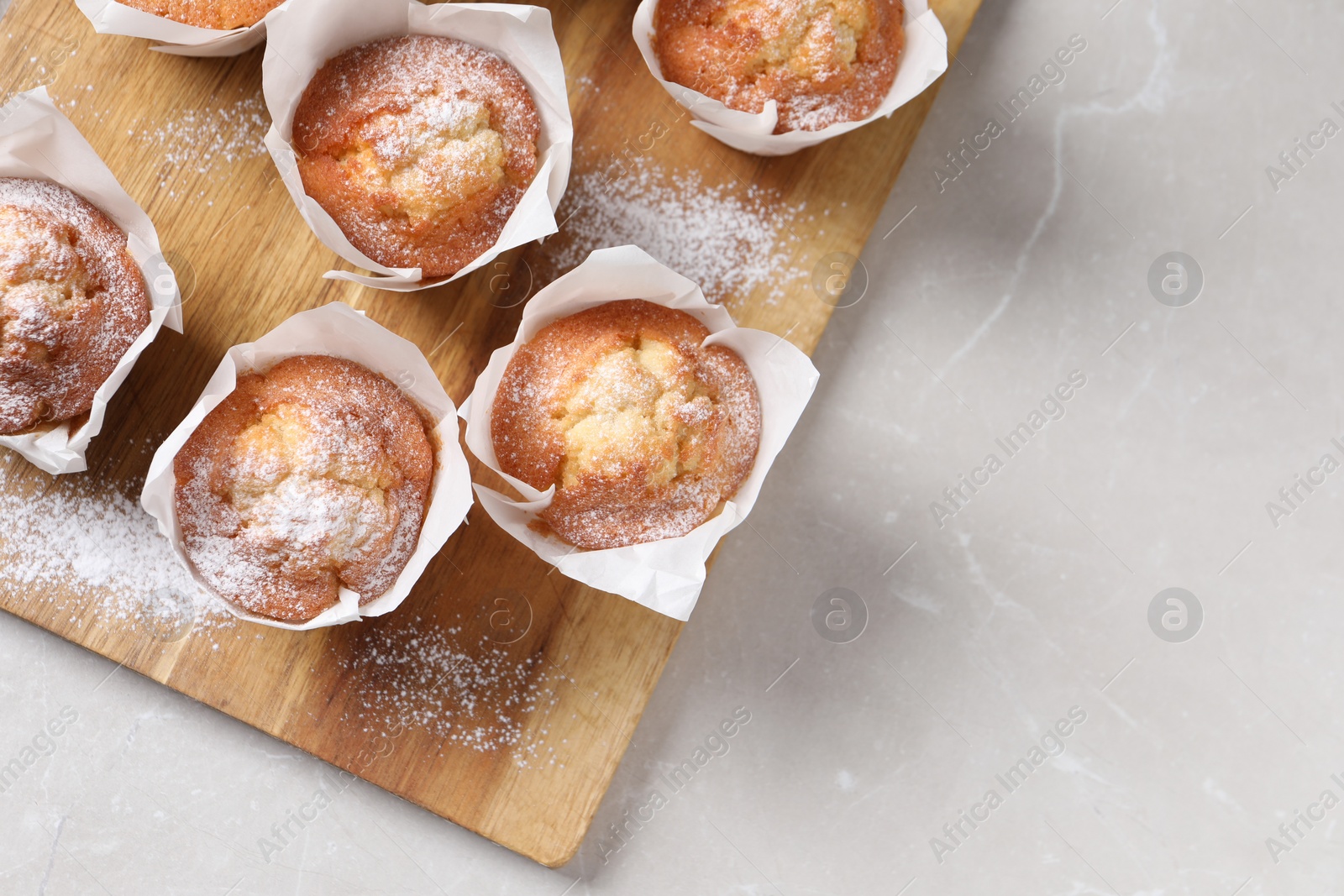 Photo of Delicious muffins on light table, top view. Space for text