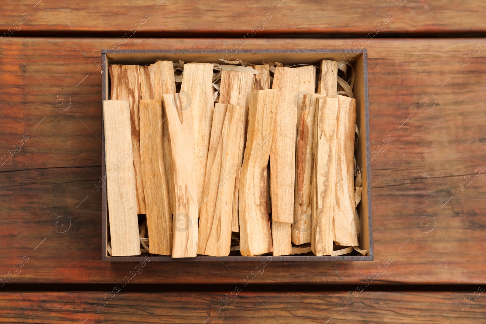 Photo of Palo Santo sticks in box on wooden table, top view