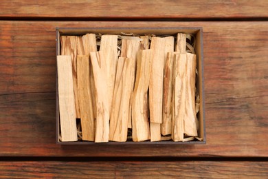 Photo of Palo Santo sticks in box on wooden table, top view