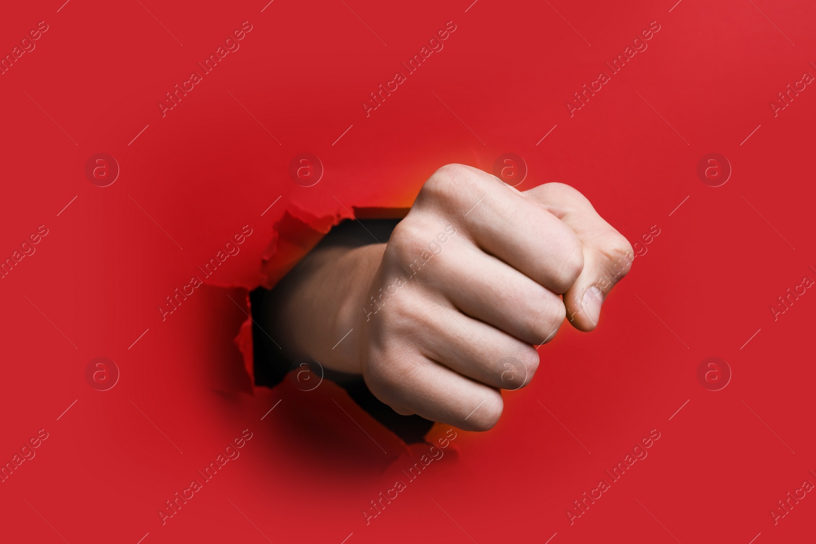 Photo of Man breaking through red paper with fist, closeup