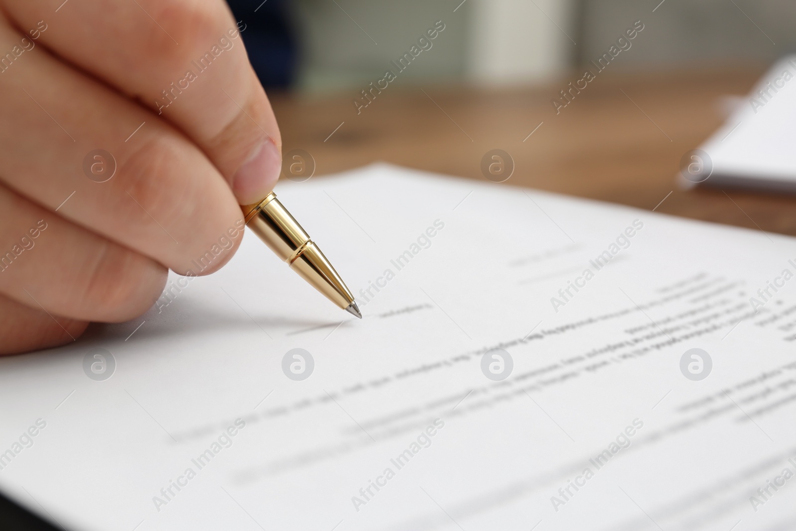 Photo of Man signing document at table, closeup view
