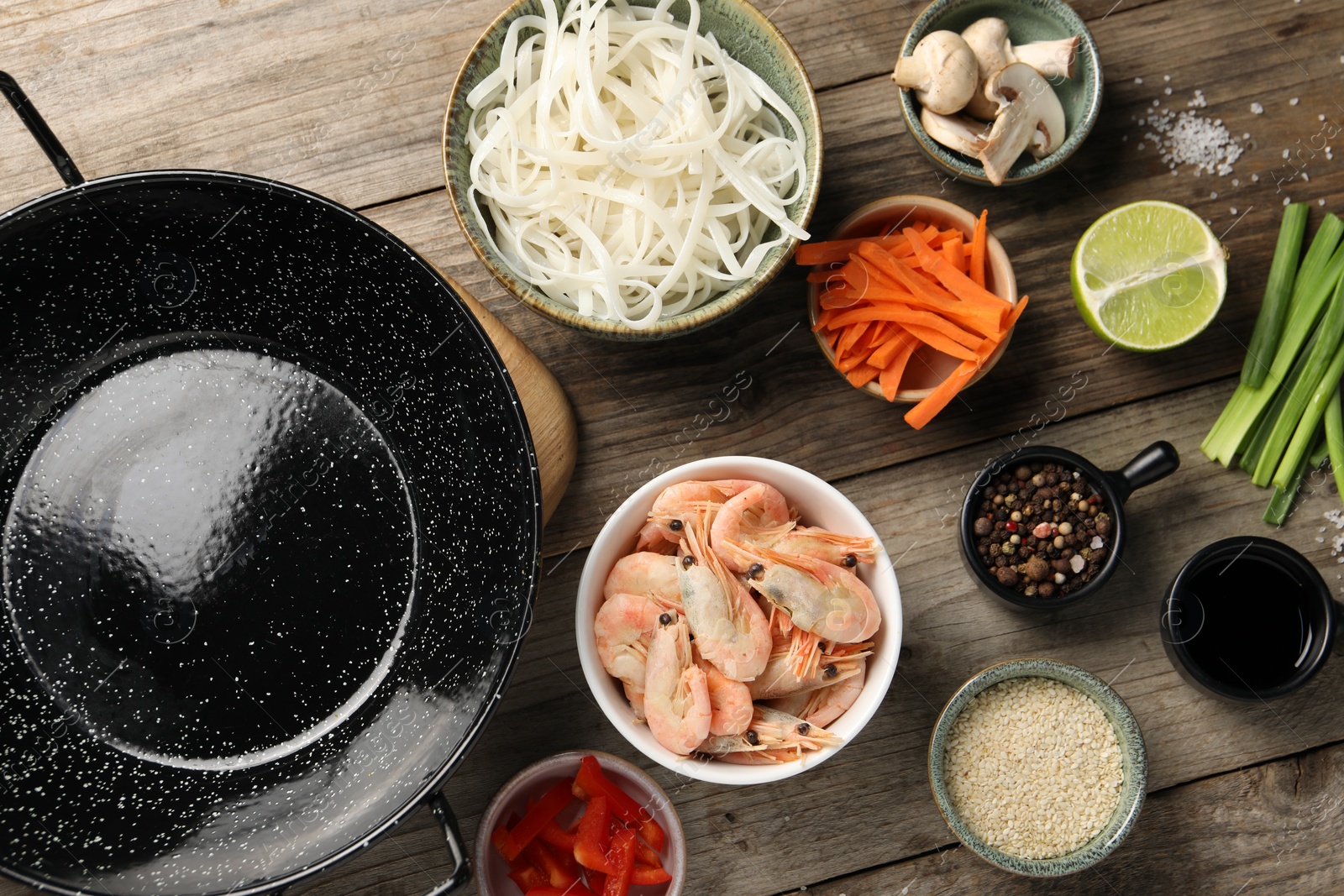 Photo of Flat lay composition with black wok, spices and products on wooden table