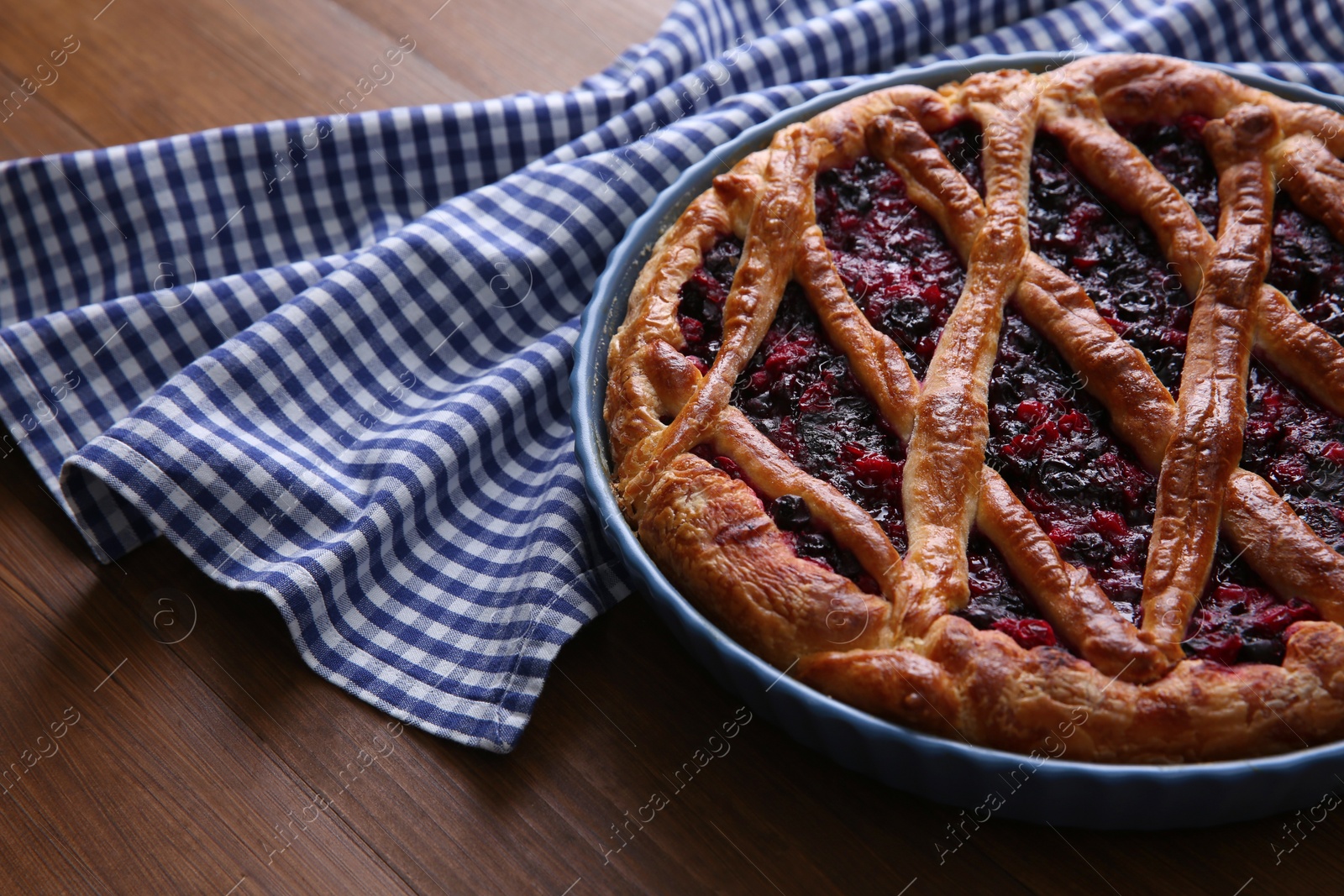 Photo of Delicious currant pie and towel on wooden table