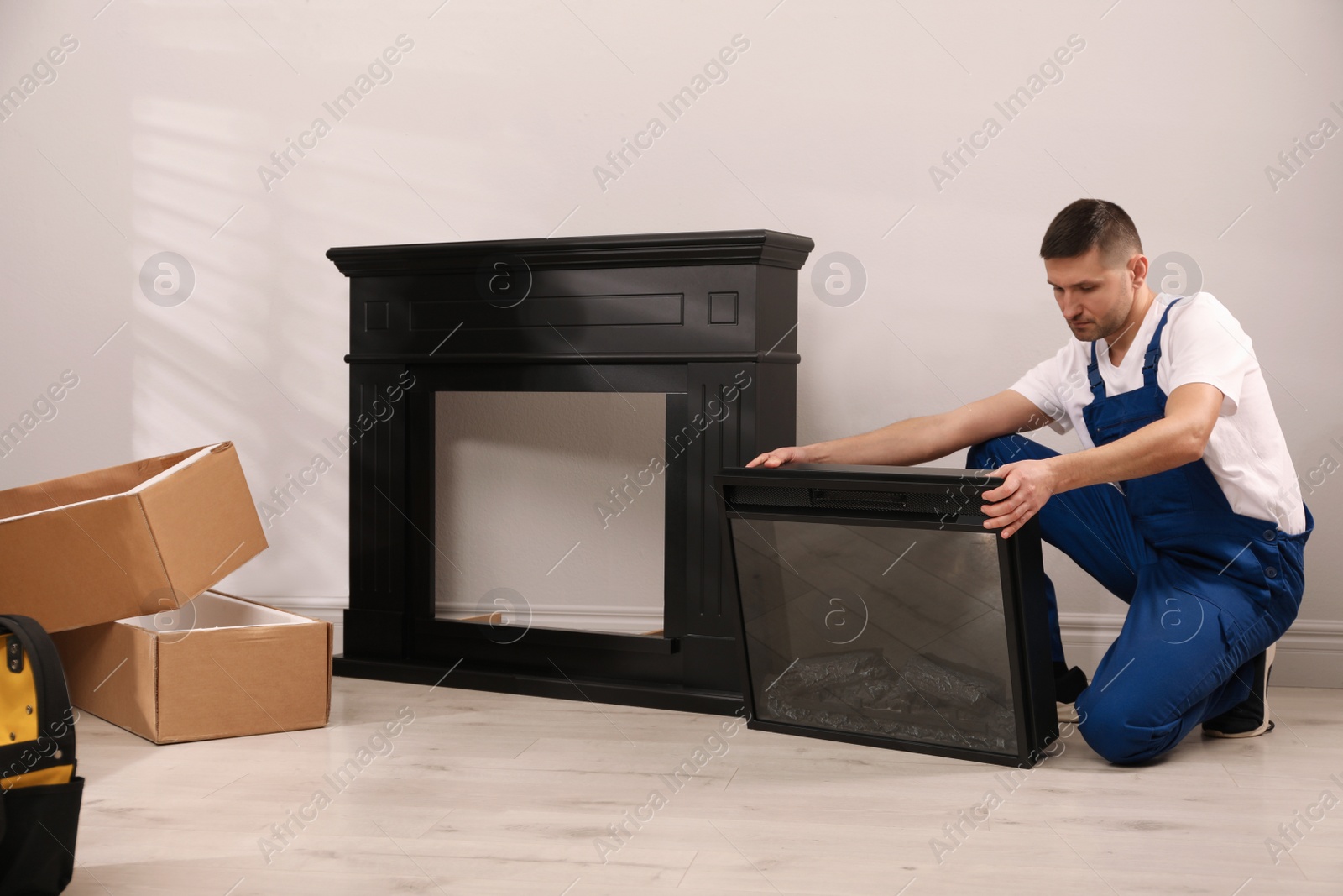 Photo of Professional technician installing electric fireplace in room