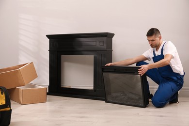 Photo of Professional technician installing electric fireplace in room