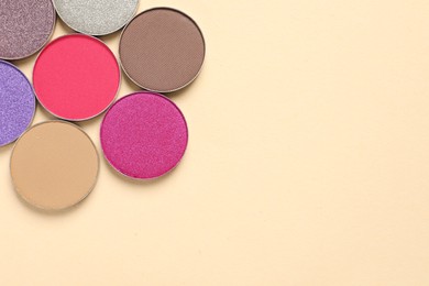 Different beautiful eye shadows on beige background, flat lay. Space for text