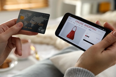 Photo of Woman with credit card using smartphone for online shopping at home, closeup