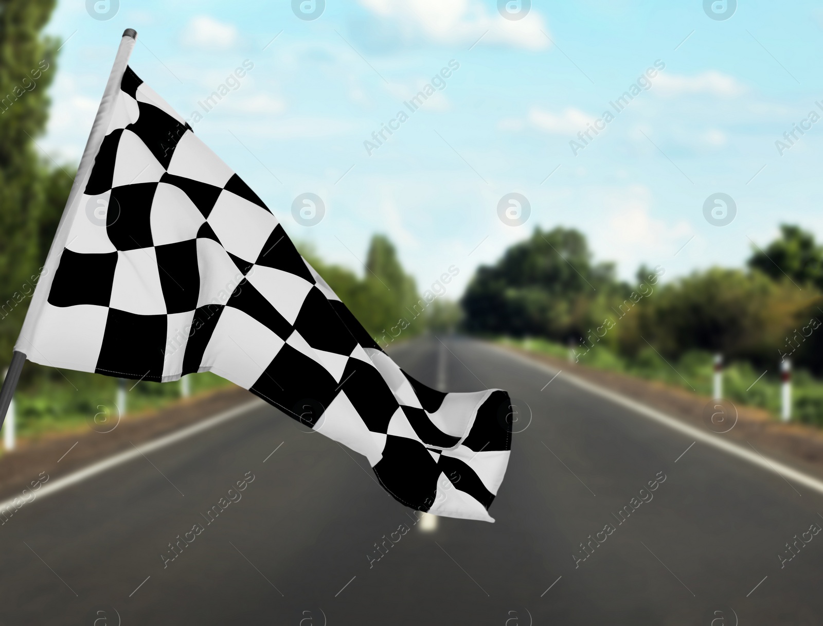 Image of Checkered racing finish flag and asphalt road outdoors