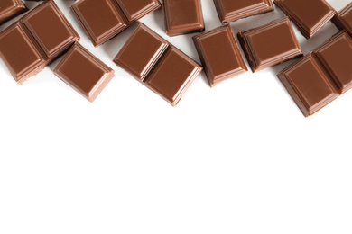 Pieces of tasty milk chocolate on white background, top view. Space for text