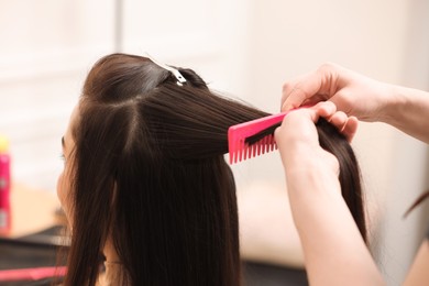 Hair styling. Professional hairdresser working with client in salon, closeup