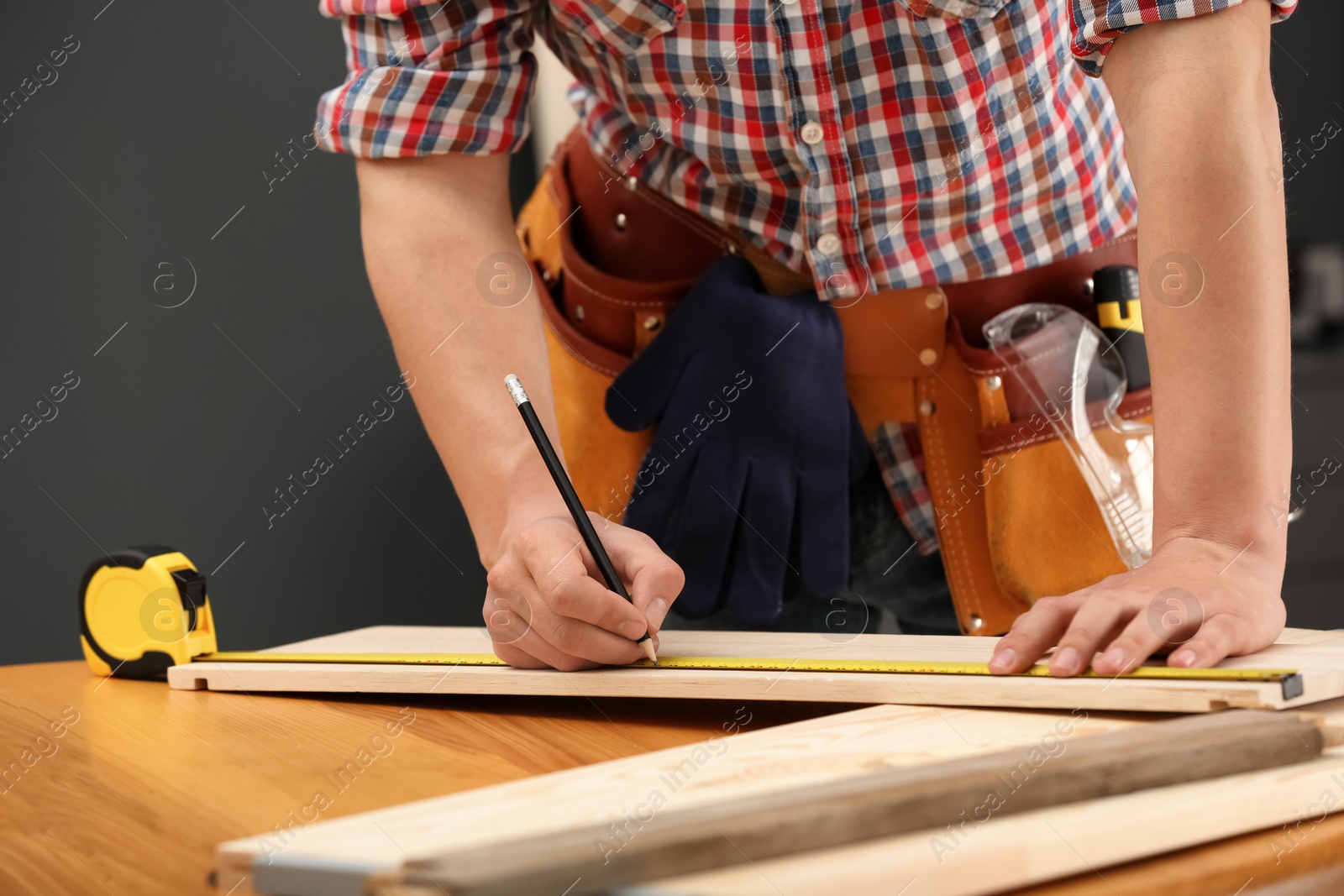 Photo of Young working man making marks on timber indoors, closeup. Home repair