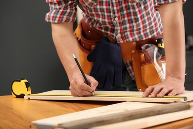 Young working man making marks on timber indoors, closeup. Home repair