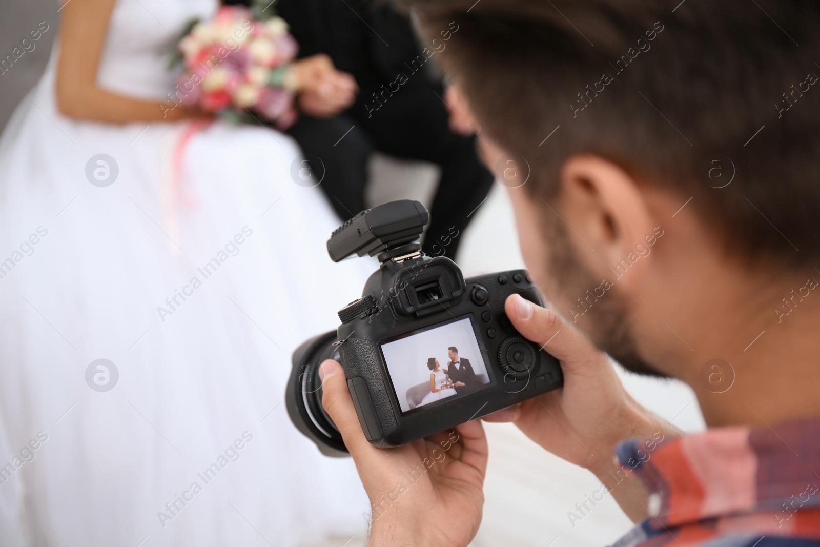 Photo of Professional photographer with camera and wedding couple in studio