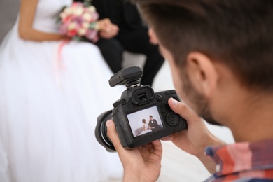 Professional photographer with camera and wedding couple in studio