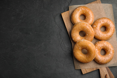 Photo of Delicious donuts on black table, top view. Space for text