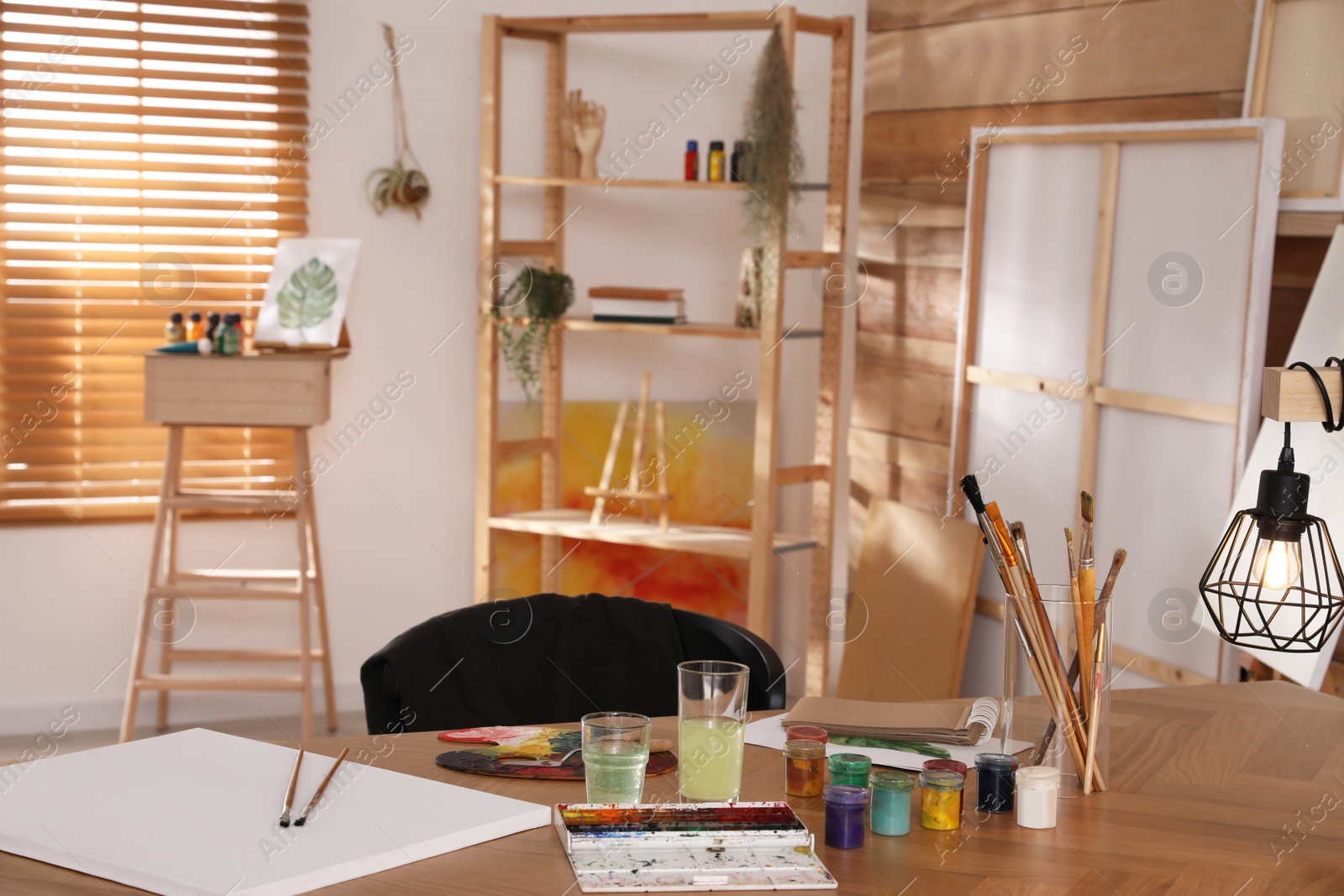 Photo of Paints and tools on wooden table in art studio