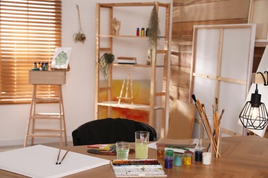 Photo of Paints and tools on wooden table in art studio