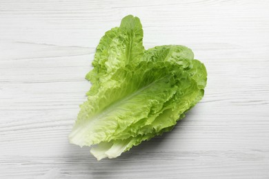 Fresh leaves of green romaine lettuce on white wooden table, top view