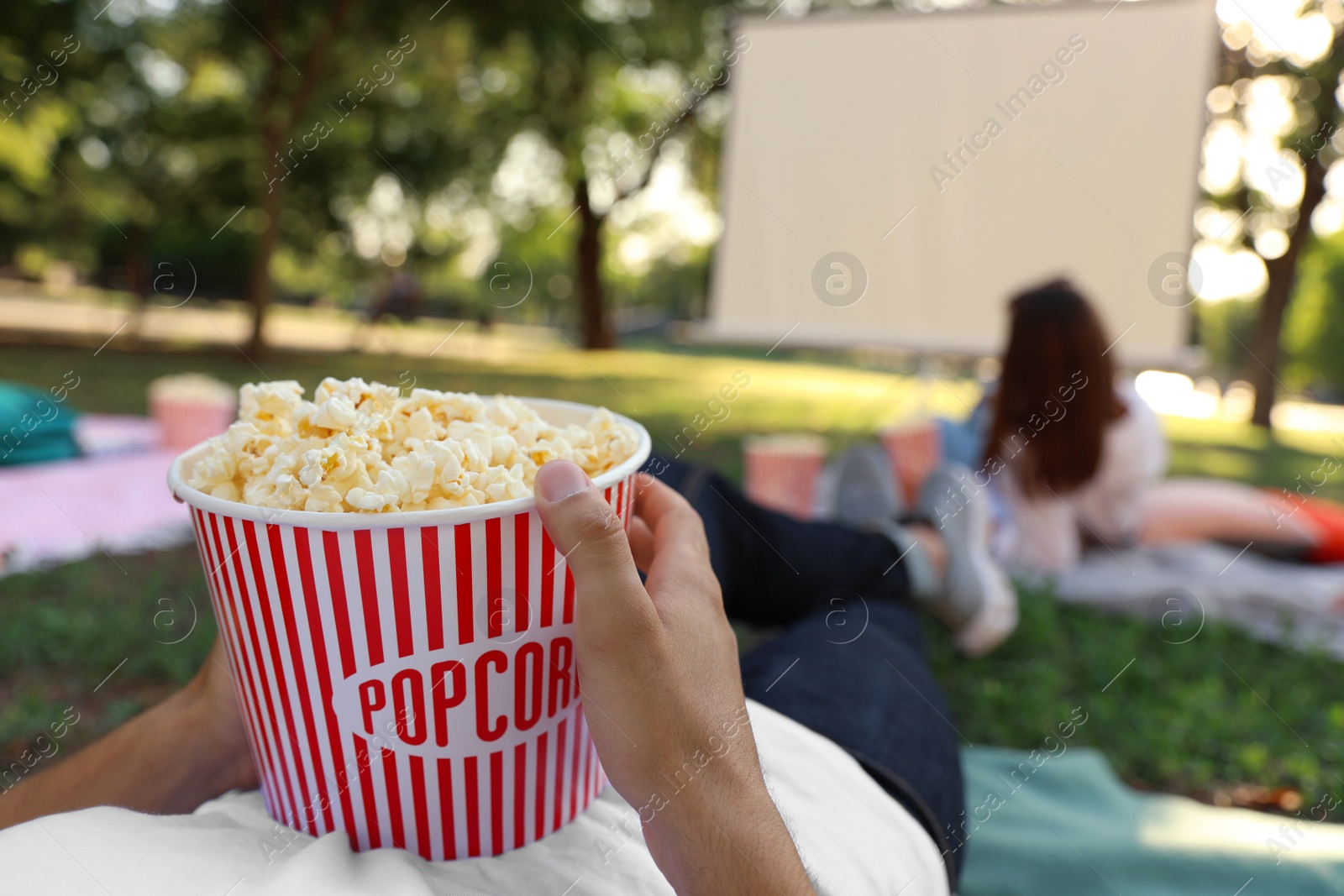 Photo of Young man with popcorn watching movie in open air cinema, closeup. Space for text