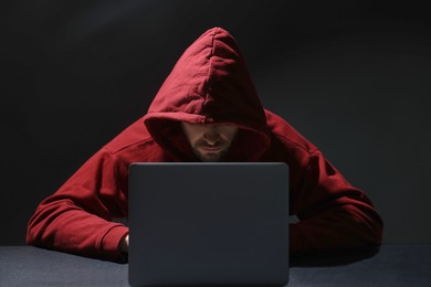 Photo of Hacker working with laptop in dark room. Cyber attack
