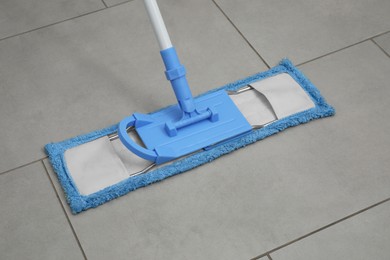Photo of Cleaning grey tiled floor with microfiber mop, closeup