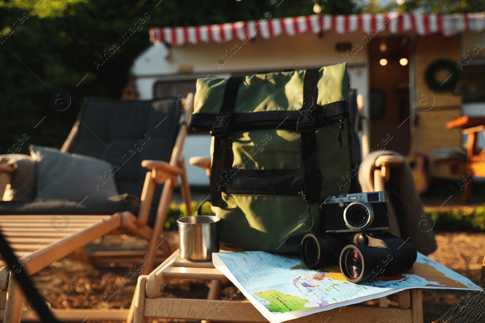 Photo of Green backpack and travel accessories on deck chair outdoors. Summer trip