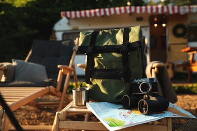 Green backpack and travel accessories on deck chair outdoors. Summer trip