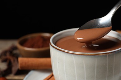 Photo of Spoon with yummy hot chocolate over cup, closeup. Space for text