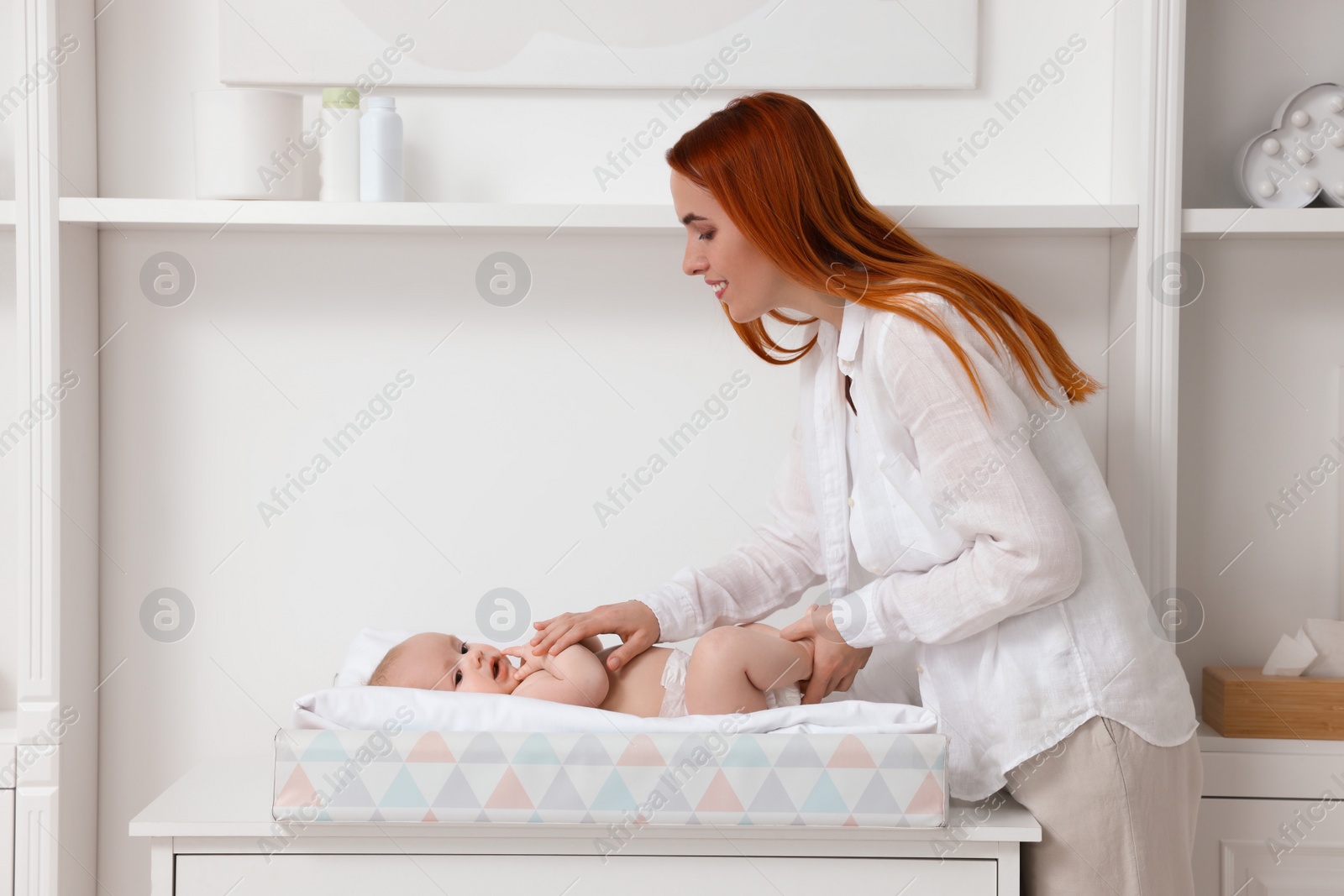 Photo of Mother with her baby at changing table indoors