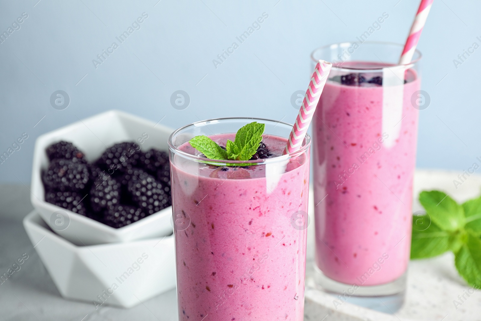 Photo of Delicious blackberry smoothie in glasses on light table