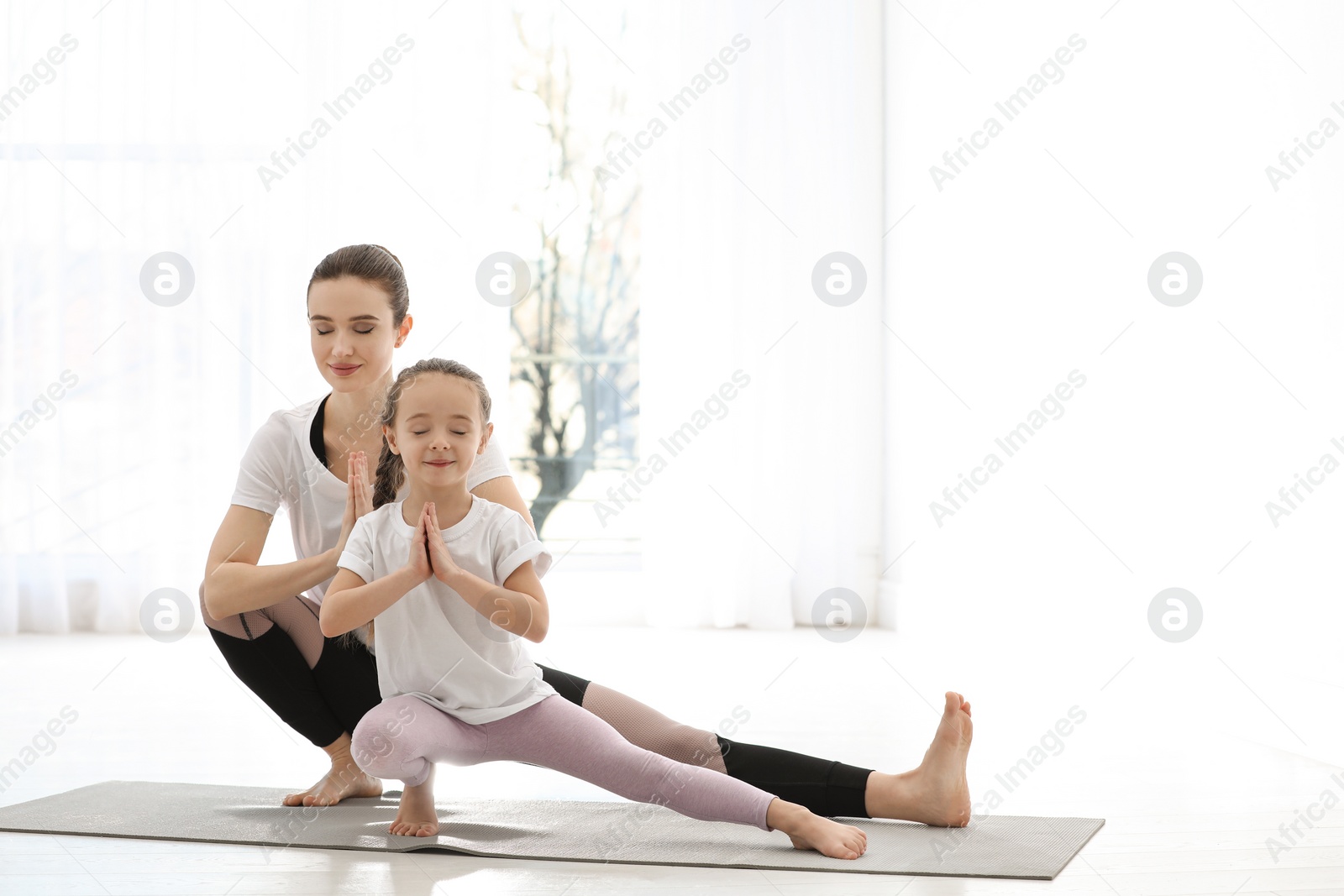 Photo of Young mother with little daughter practicing yoga at home