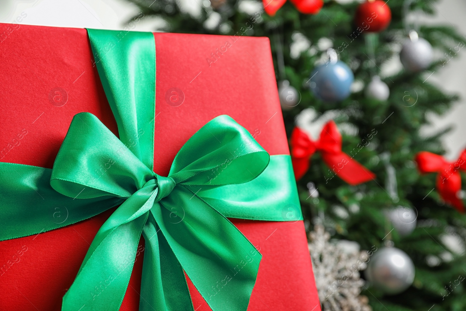 Photo of Beautiful gift box and blurred Christmas tree on background